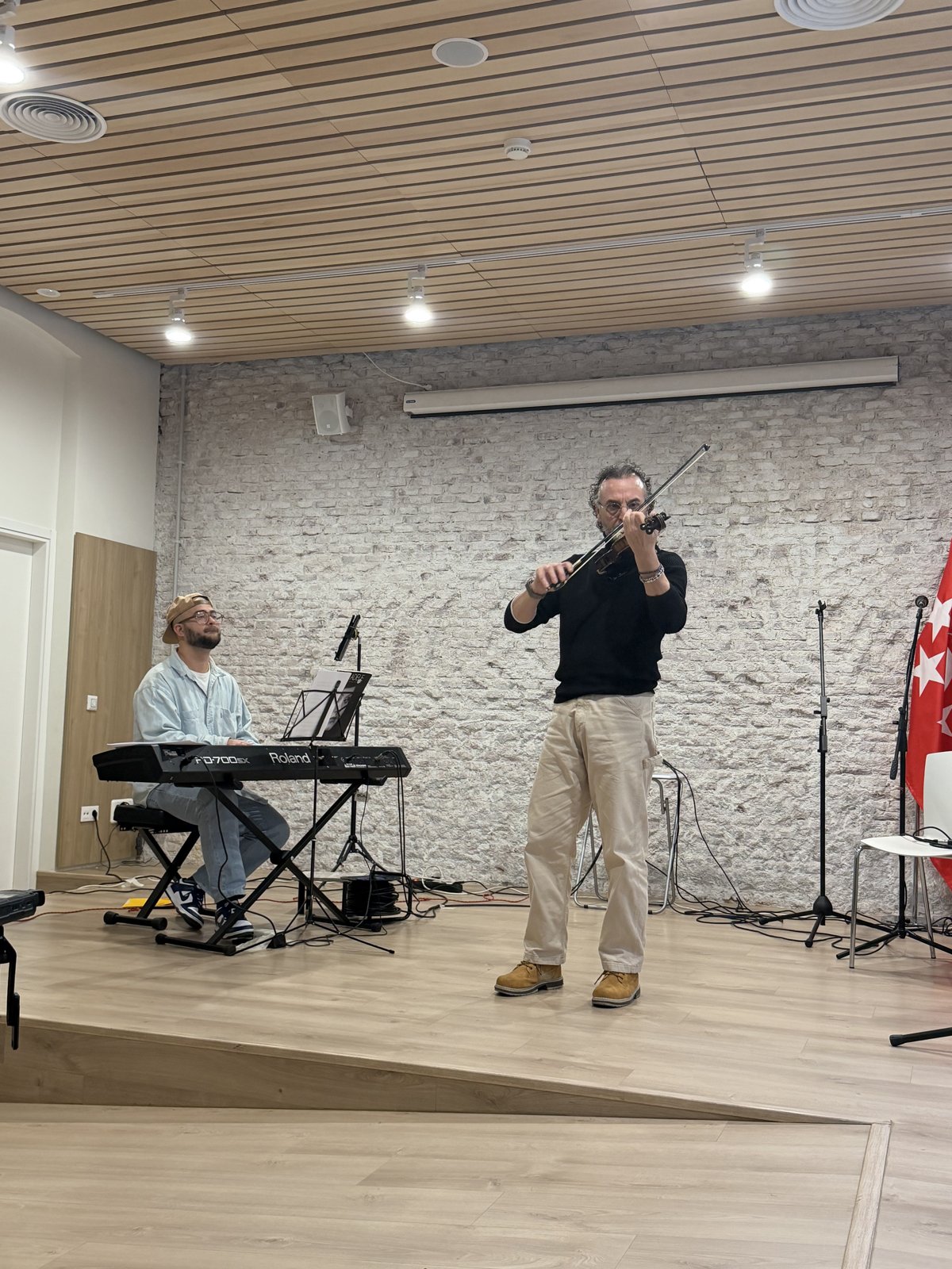 Alumno tocando el violín sobre el escenario acompañado al piano